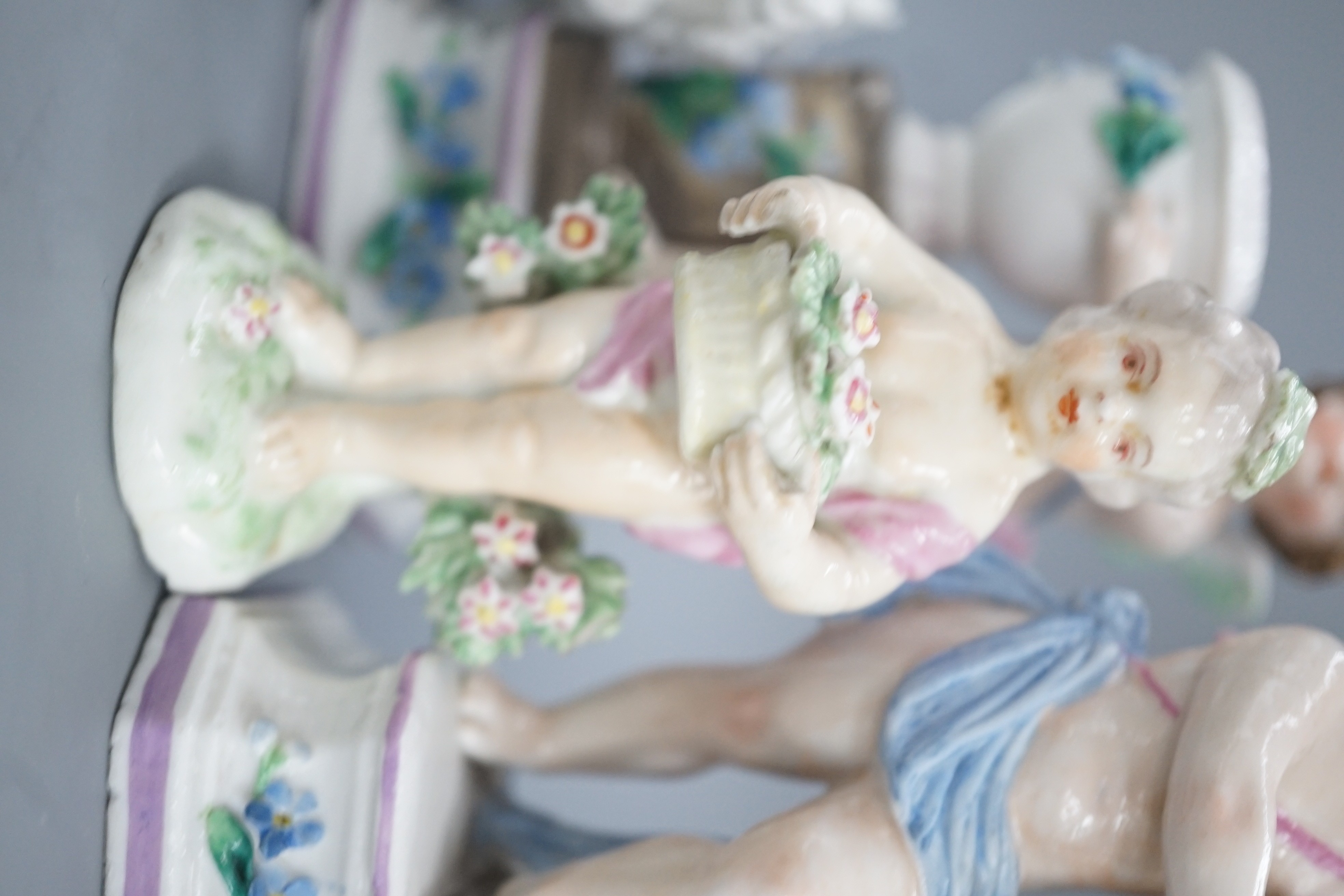 A pair of Continental porcelain cherub candlesticks, 13.5cm, a figural bonbon and a Derby figure